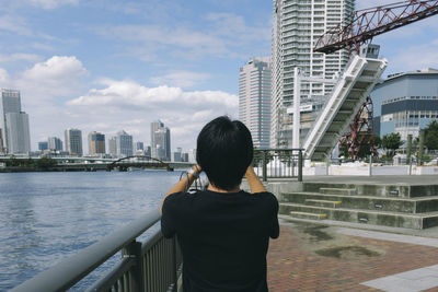 Rear view of man standing by railing against buildings