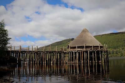 Wooden posts in lake against sky