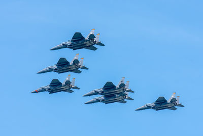 Low angle view of airshow against clear blue sky