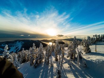 Snow covered landscape against sky during sunset