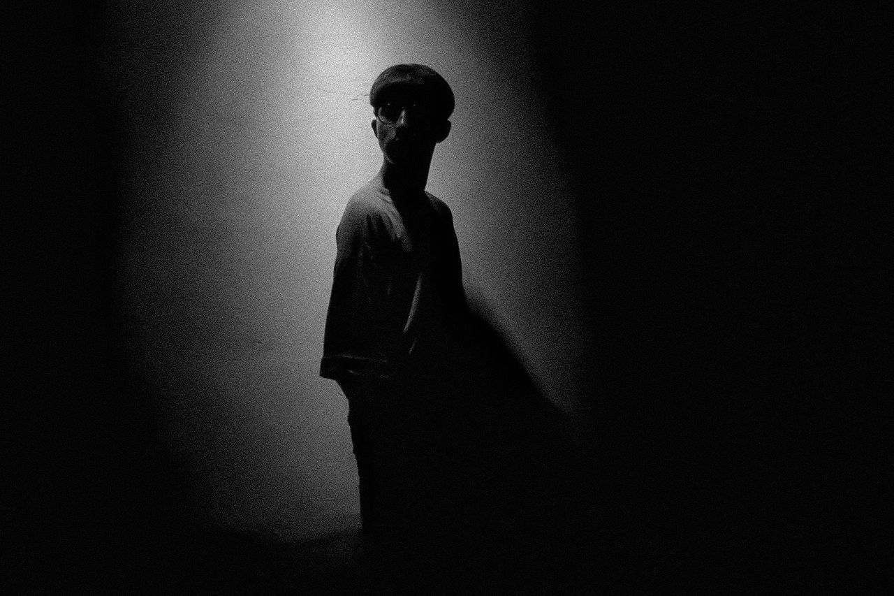 YOUNG MAN STANDING AGAINST WALL