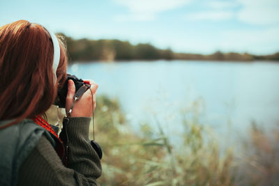 Rear view of woman photographing lake