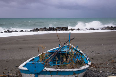 Fishing boat on beach against sky