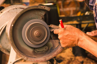 Midsection of man sharpening metal on grinder