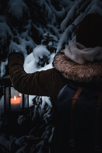 Person carrying lantern in dark winterly forest