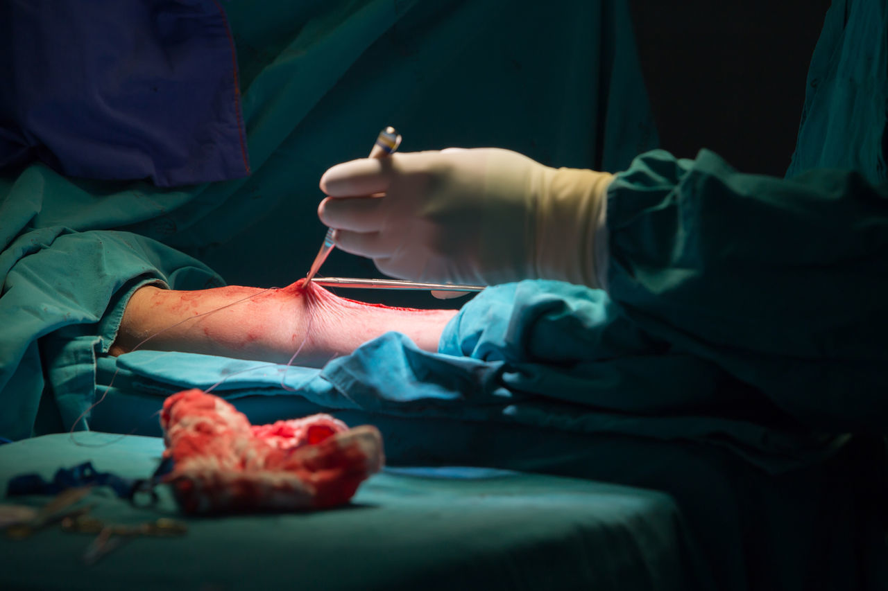 MIDSECTION OF A PERSON HOLDING HANDS IN A MESSY ROOM