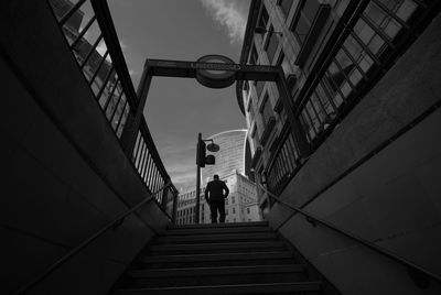 Low angle view of man walking on staircase in city