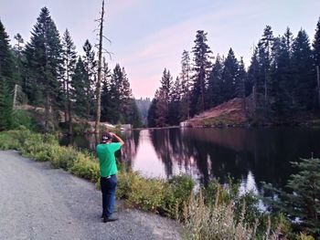 Rear view of man standing on road amidst trees