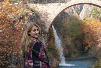 Young woman standing against waterfall