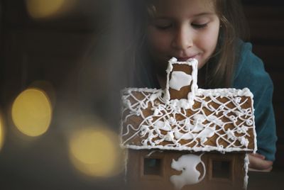 Close-up of girl with gingerbread house on table