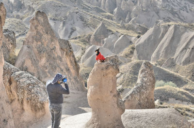 Man photographing dog on rock formation