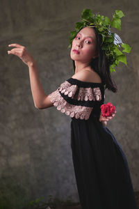 Portrait of a beautiful young woman standing against wall