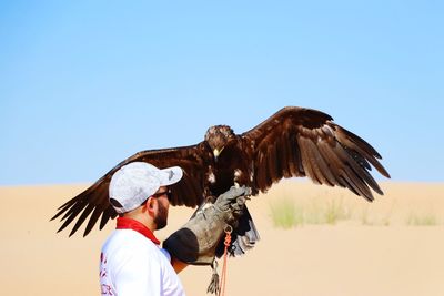 Man holding eagle at desert