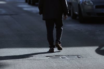 Low section of man walking on road