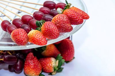 Close-up of fruits in skewers against white background