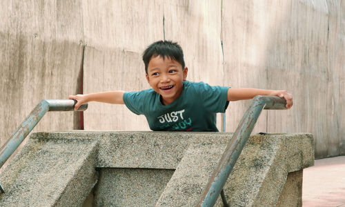 Portrait of boy sitting on railing