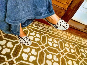 Low section of woman sitting at home against tiled floor