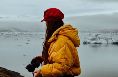 Side view of woman with umbrella standing in rain