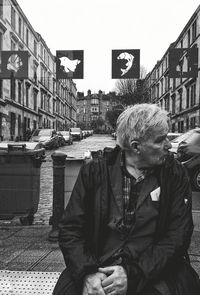 Portrait of man sitting on street in city