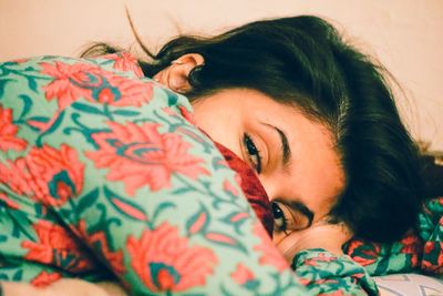 Close-up portrait of young woman relaxing on bed at home