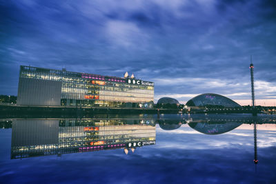 City at waterfront against cloudy sky