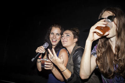 Smiling young woman drinking at night