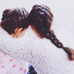 Sisters with braided hair against wall