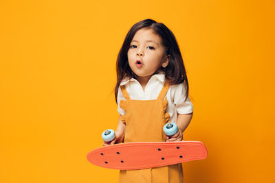 Portrait of young woman against yellow background