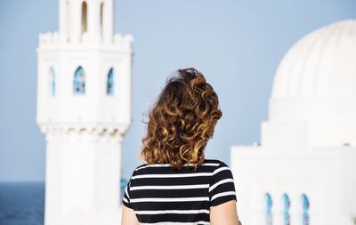 Rear view of a woman against cropped built structure