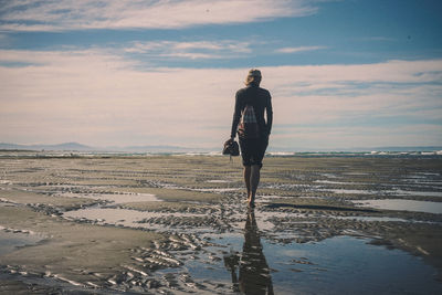 Man walking on beach against sky