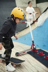 Boy learning how to skateboard in indoor skatepark