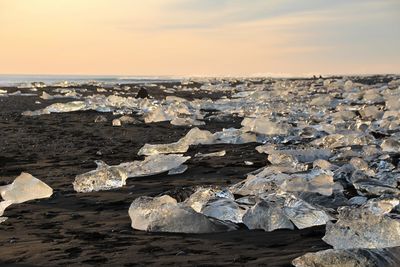 Aerial view of rocks by sea against sky during sunset