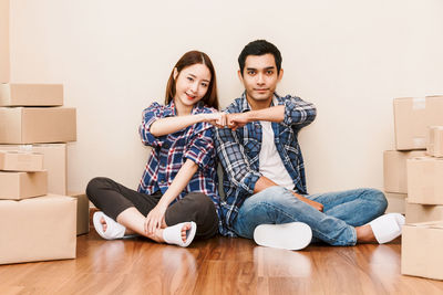 Couple doing fist bump while sitting on floor at new home