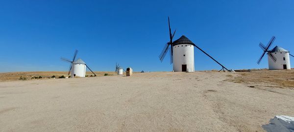 Lighthouse by sea against clear blue sky