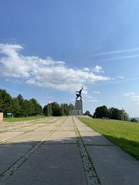 Road amidst field against sky