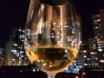 Close-up of wine in illuminated city at night