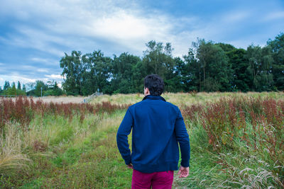 Rear view of man on field against sky