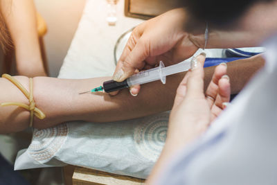 Cropped hands of female doctor injecting syringe in patient arm