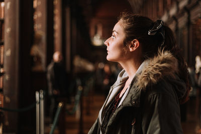 Contemplating young woman looking away while standing in city at night