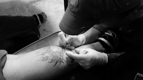 Artist tattooing on man leg at studio