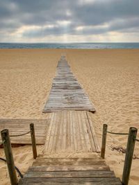 Wooden pier on beach against sky