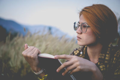 Portrait of young woman holding sunglasses