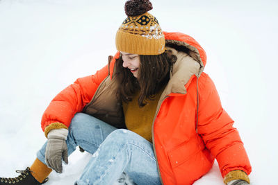 Full length of senior woman sitting on snow