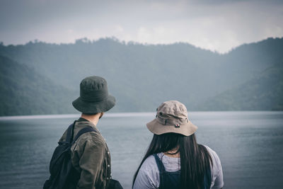 Rear view of woman looking at lake against mountain range