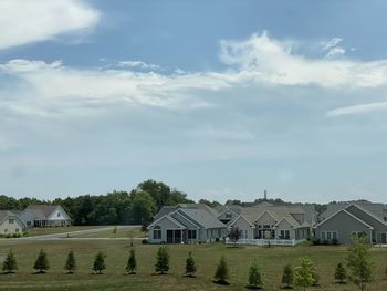 Houses on field by buildings against sky