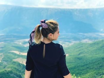 Young woman standing by sea against mountain