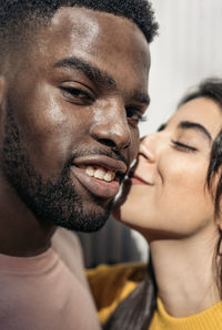 Man kissing woman against wall