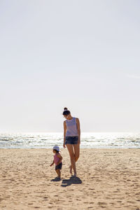 Woman walks with her little son on a sandy beach near the sea in the summer