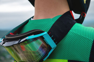 Close-up of protective goggles mask on the neck of a young cyclist rider outdoors. view from the