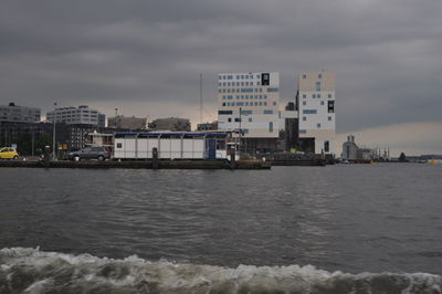 Sea by buildings against sky in city